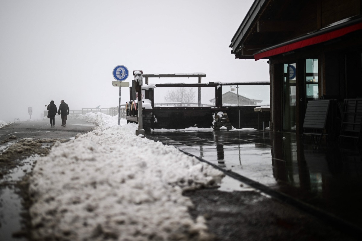 People walk past snow-covered chalets after heavy snowfall at the Aravis Pass (Col des Aravis), near La Clusaz in east-central France, on April 17, 2025. Photo by OLIVIER CHASSIGNOLE / AFP