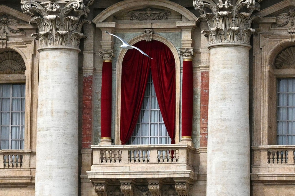 A seagull flies in front of the central loggia at St Peter's square following the death of Pope Francis in the Vatican on April 21, 2025. (Photo by Andreas Solaro / AFP)