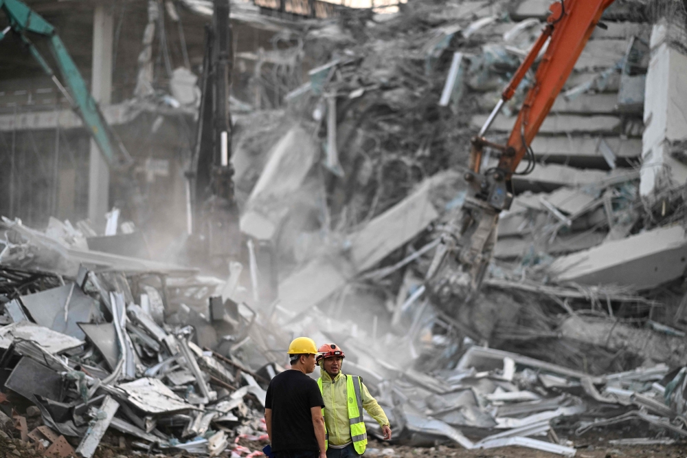 Heavy construction equipment is used by rescue teams trying to find people trapped in the rubble at the site of an under-construction building collapse in Bangkok on March 29, 2025. (Photo by Manan Vatsyayana / AFP)

