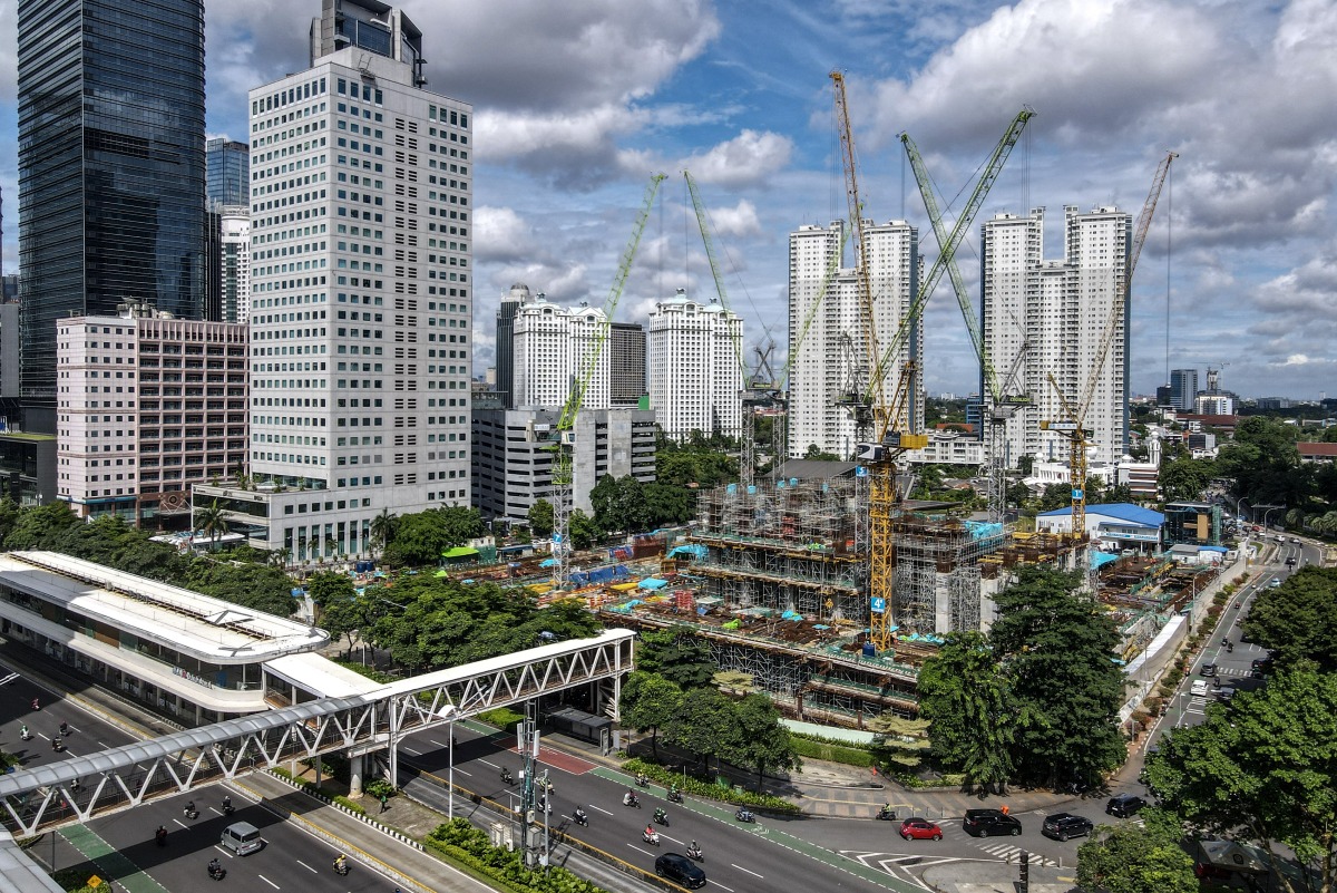 This aerial picture shows an under construction building among skyscrapers in Jakarta's business district on April 14, 2025. (Photo by BAY ISMOYO / AFP)