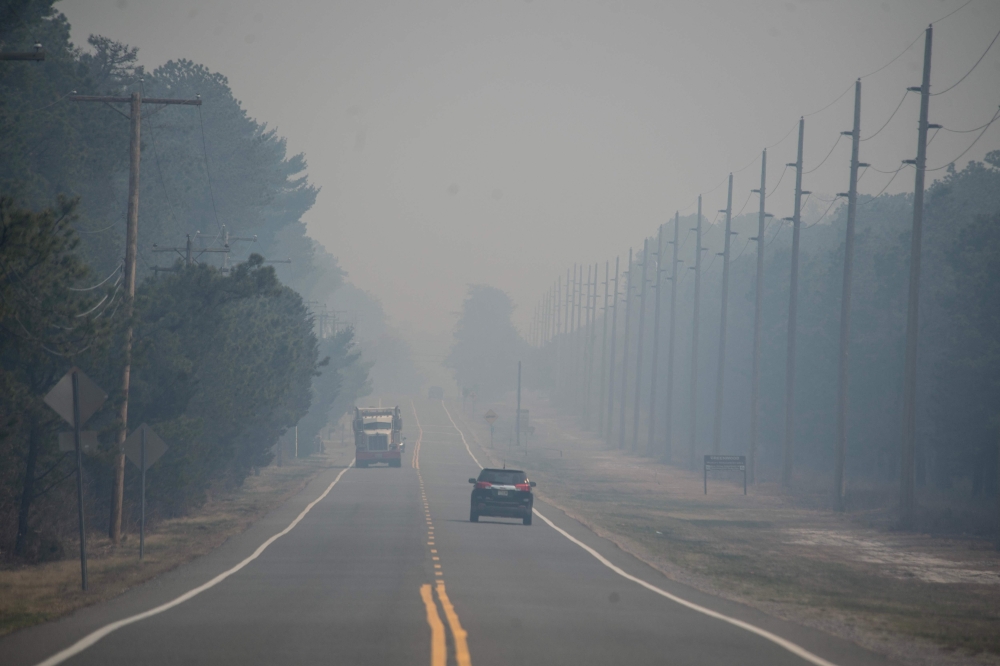 Smoke from the Jones Road Fire covers a road near Lacey Township in Ocean County, New Jersey, on April 23, 2025. (Photo by Matthew Hatcher / AFP)