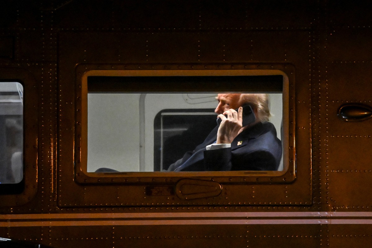 US President Donald Trump uses a cellphone aboard Marine One before it departs Leesburg Executive Airport in Leesburg, Virginia, on April 24, 2025. Photo by Alex WROBLEWSKI / AFP.
