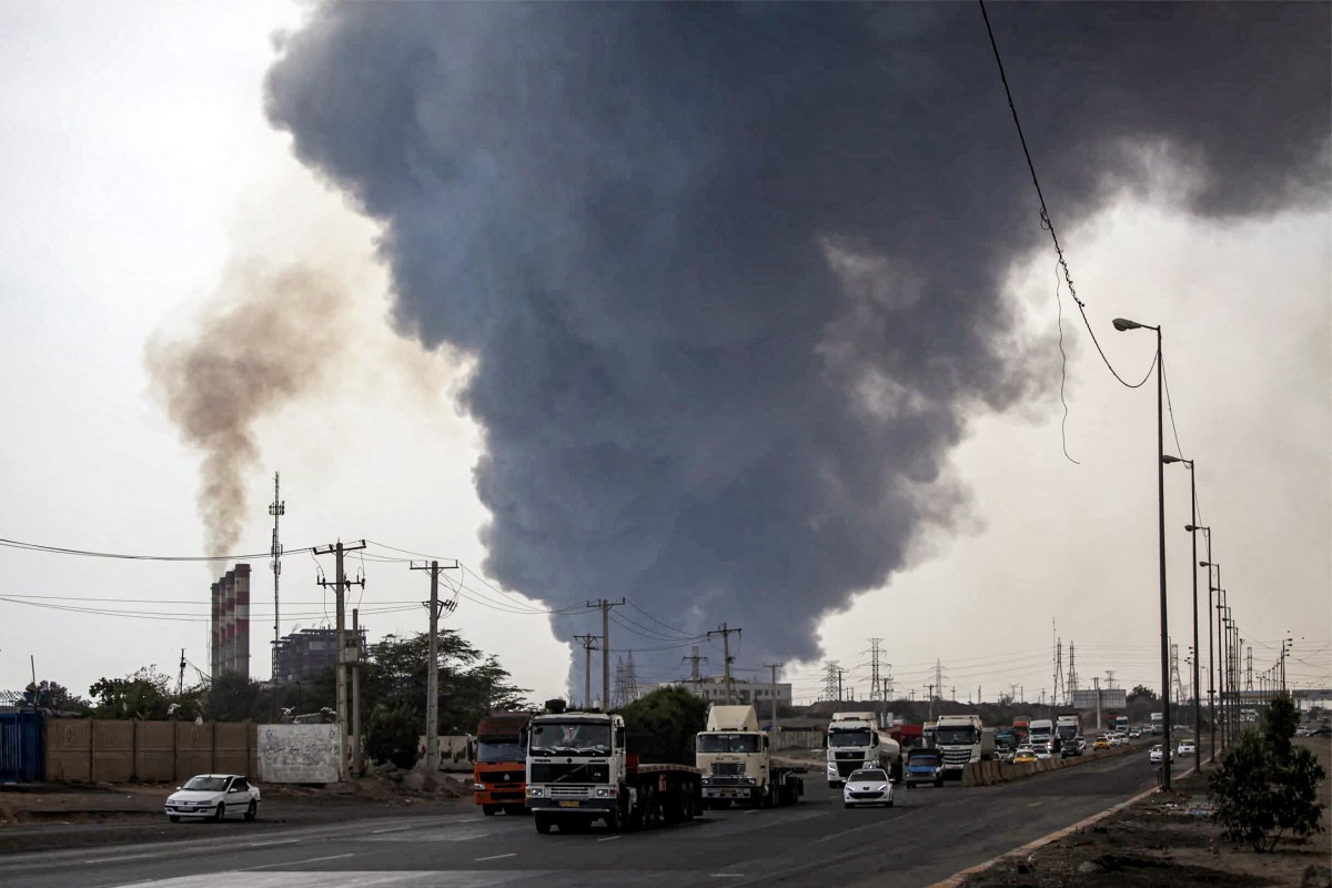 A thick plume of smoke billows as motorists drive their vehicles along a highway near the source of an explosion at the Shahid Rajaee port dock southwest of Bandar Abbas in the Iranian province of Hormozgan on April 26, 2025. Photo by Mohammad Rasole MORADI / IRNA / AFP.