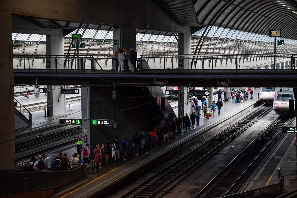 Passengers walk along a platform to board a train at Santa Justa railway station in Seville on April 29, 2025, the day after a massive power cut affecting the entire Iberian peninsula and the south of France. Photo by CRISTINA QUICLER / AFP
