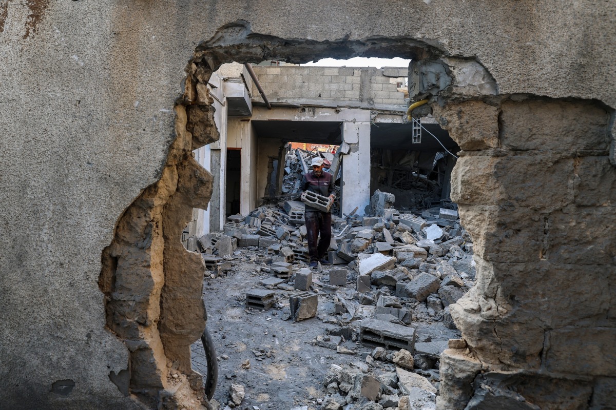 A man carries salvaged concrete blocks inside a building hit in an Israeli strike in the Bureij camp for Palestinian refugees in the central Gaza Strip on May 2, 2025. (Photo by Eyad BABA / AFP)