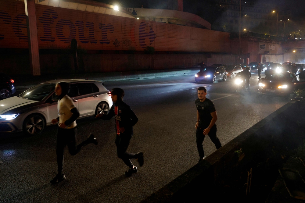 Paris Saint-Germain (PSG) supporters run after police used tear gas to disperse them after a group of supporters blocked the highway near the Parc des Princes Stadium in Paris on May 7, 2025. (Photo by Geoffroy Van Der Hasselt / AFP)