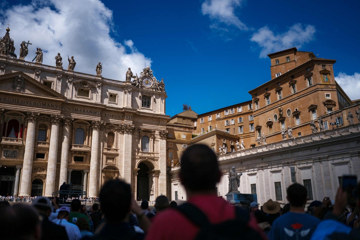 People stand on St Peter's Square after black smoke billowed from a chimney over the Sistine Chapel, on the second day of the conclave, in the Vatican on May 8, 2025. Photo by Dimitar DILKOFF / AFP