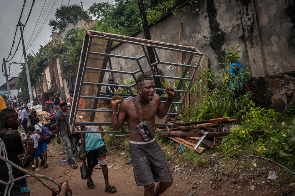 A man carries a window torn from a house during demolition in Kinshasa, Democratic Republic of Congo, on May 8, 2025. (Photo by Glody Murhabazi / AFP)
