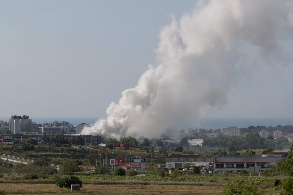 A picture taken on May 10, 2025 shows smoke billowing from a building storing pool cleaning products, in the coastal city of Vilanova i la Geltru, south of Barcelona. (Photo by Lluis Gene / AFP)