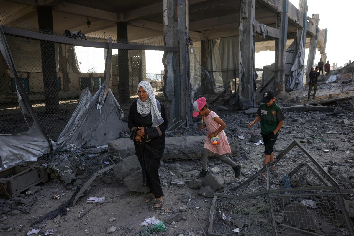 Displaced Palestinians walk amid the rubble of an UNRWA school-turned-shelter, heavily damaged in an overnight Israeli strike in Jabalia in the northern Gaza Strip on May 10, 2025. (Photo by BASHAR TALEB / AFP)
