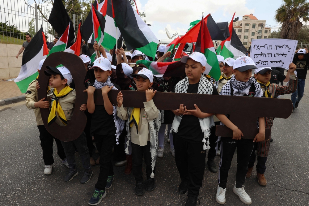 Palestinian children hold up a cutout symbolising the key to houses left by Palestinians in 1948 as they take part in a rally to commemorate the 77th anniversary of the 