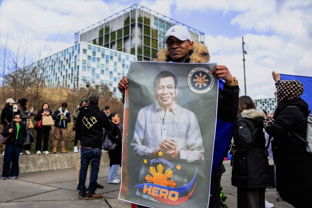 A supporter holds a portrait of former Philippine president Rodrigo Duterte in front of the International Criminal Court (ICC) in The Hague, Netherlands, on March 14, 2025. (Photo by Nicolas Tucat / ANP / AFP)
