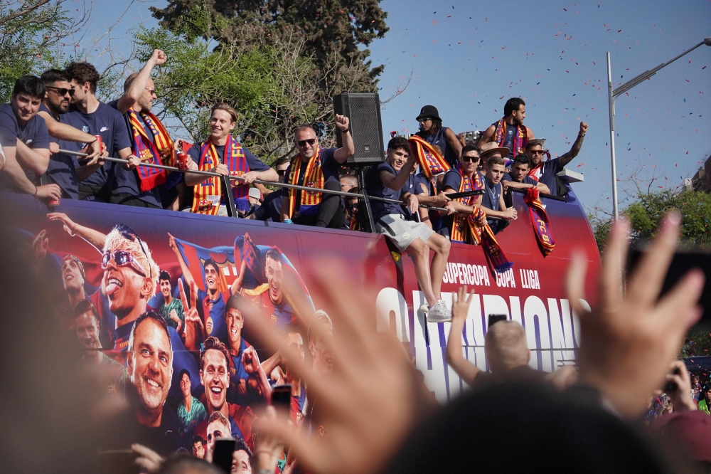 Barcelona's German coach Hans-Dieter Flick (C) and players ride in an open top bus to celebrate winning their 28th La Liga title in Barcelona, on May 16, 2025. (Photo by Manaure Quintero / AFP)
