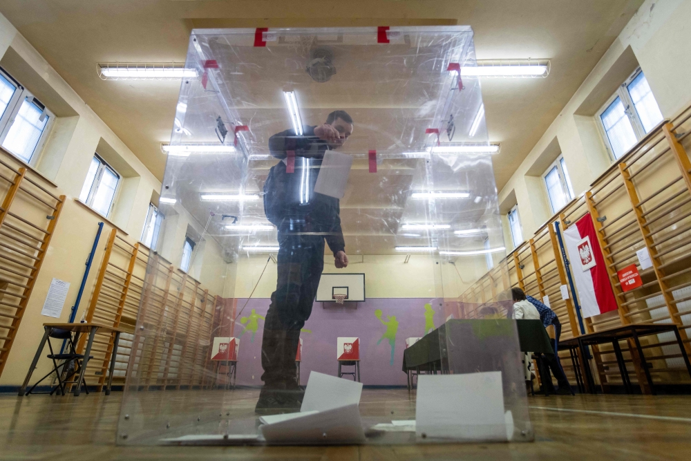 A voter casts his voting ballot at a polling station in Warsaw, Poland, on May 18, 2025, during the first round of the presidential elections. (Photo by Wojtek Radwanski / AFP)