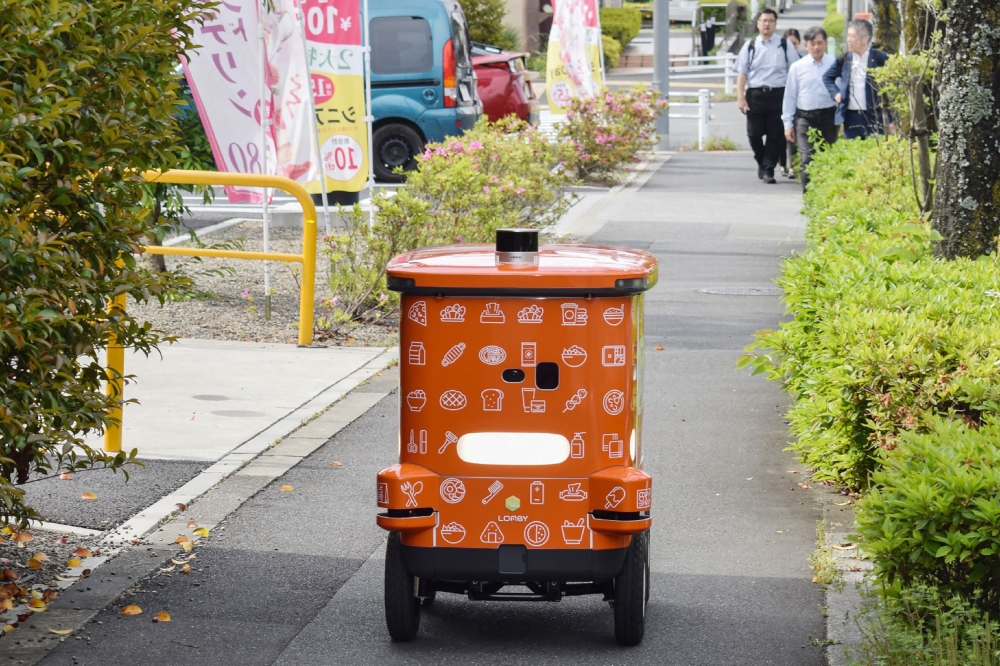 This photo taken on May 15, 2025 shows an automated robot on wheels from convenience store chain 7-Eleven delivering items during a demonstration in the Hachioji area of Tokyo. (Photo by JIJI Press / AFP) 