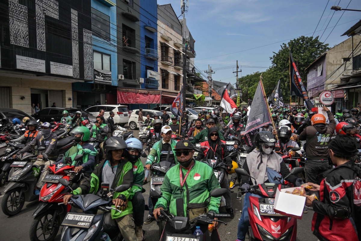 Drivers for ride hailing platforms, demanding a 10 percent cap on app commission charges amid high platform fees imposed onto them, demonstrate outside the Gojek office in Surabaya on May 20, 2025. (Photo by JUNI KRISWANTO / AFP)
