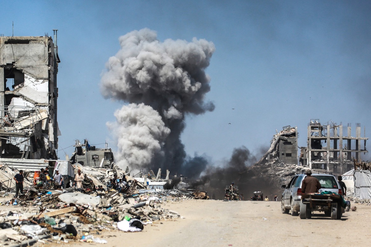 TOPSHOT - People watch as smoke billows following an Israeli strike in Jabalia, in the northern Gaza Strip on May 25, 2025. (Photo by Bashar TALEB / AFP)
