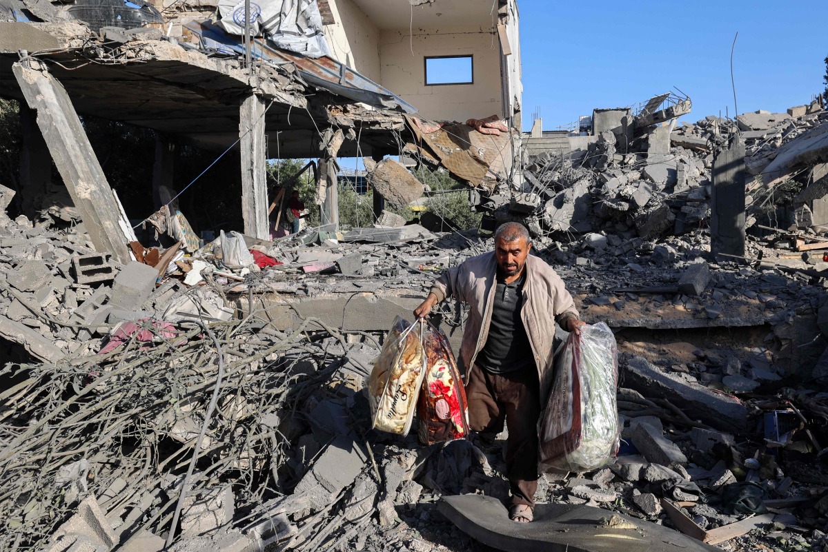 A Palestinian man carries items he salvaged from a house targeted in an Israeli strike at the Nuseirat camp for refugees in the central Gaza Strip on May 24, 2025. (Photo by Eyad BABA / AFP)
