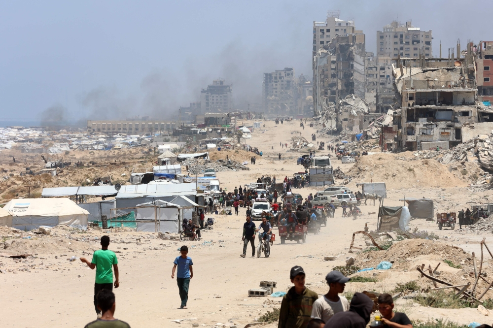 Palestinians transport their belongings as they flee the northern Gaza Strip toward the south, along the coastal al-Rashid road on May 25, 2025. (Photo by Omar Al-Qattaa / AFP)