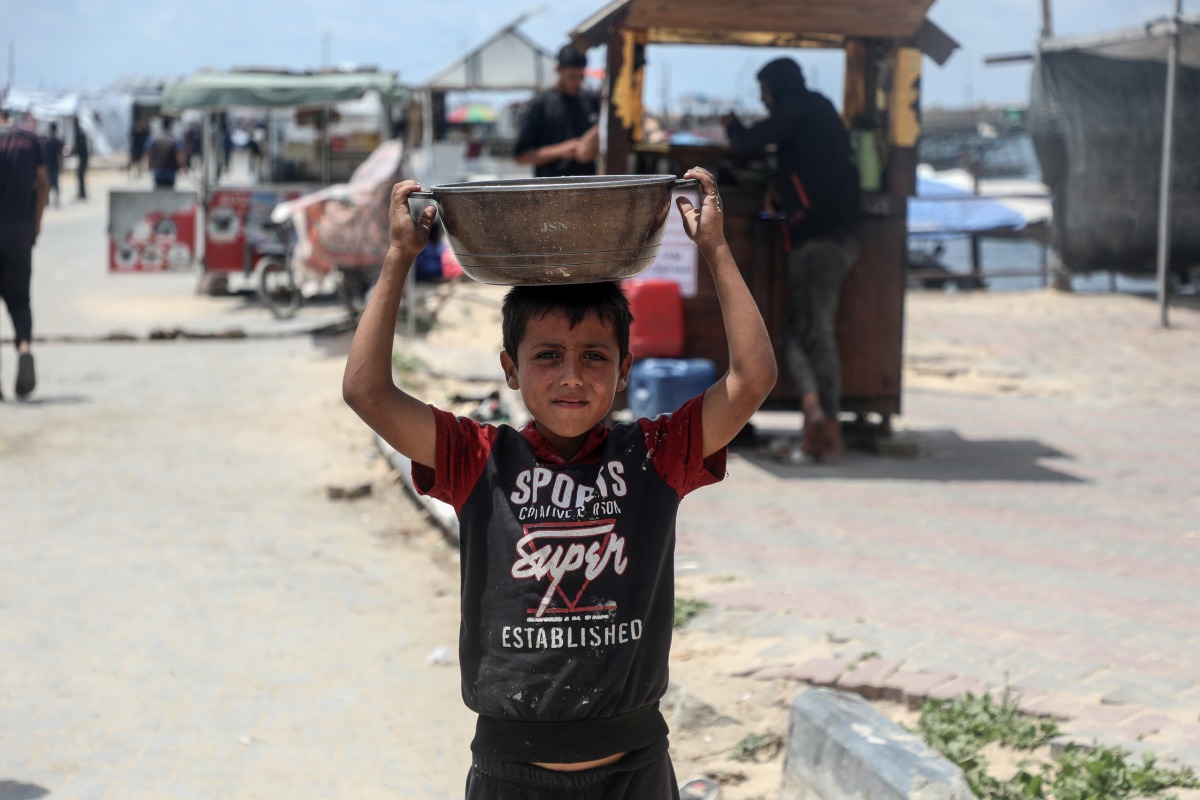 A Palestinian boy is seen with free food received from a food distribution center in Gaza City, on May 22, 2025. (Photo by Rizek Abdeljawad/Xinhua)

