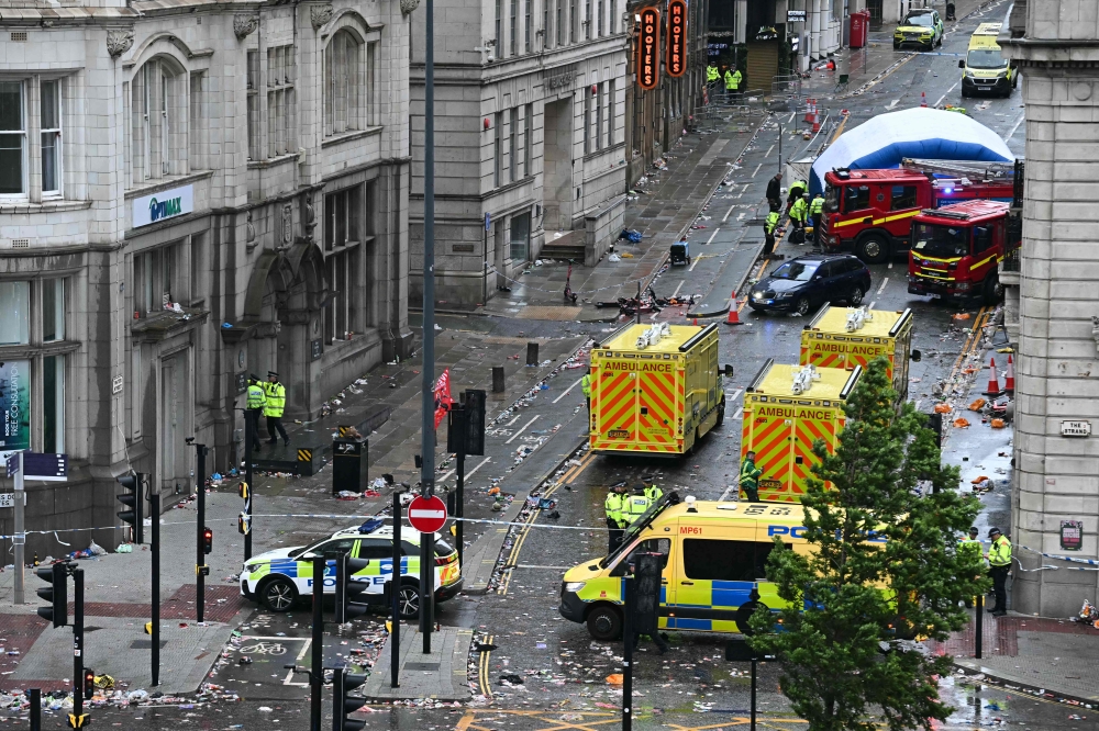 Police officers cover with an inflatable tent, behind a firefighter vehicle, the tents delimiting the scene of an incident in Water Street. (Photo by Paul Ellis / AFP)
 