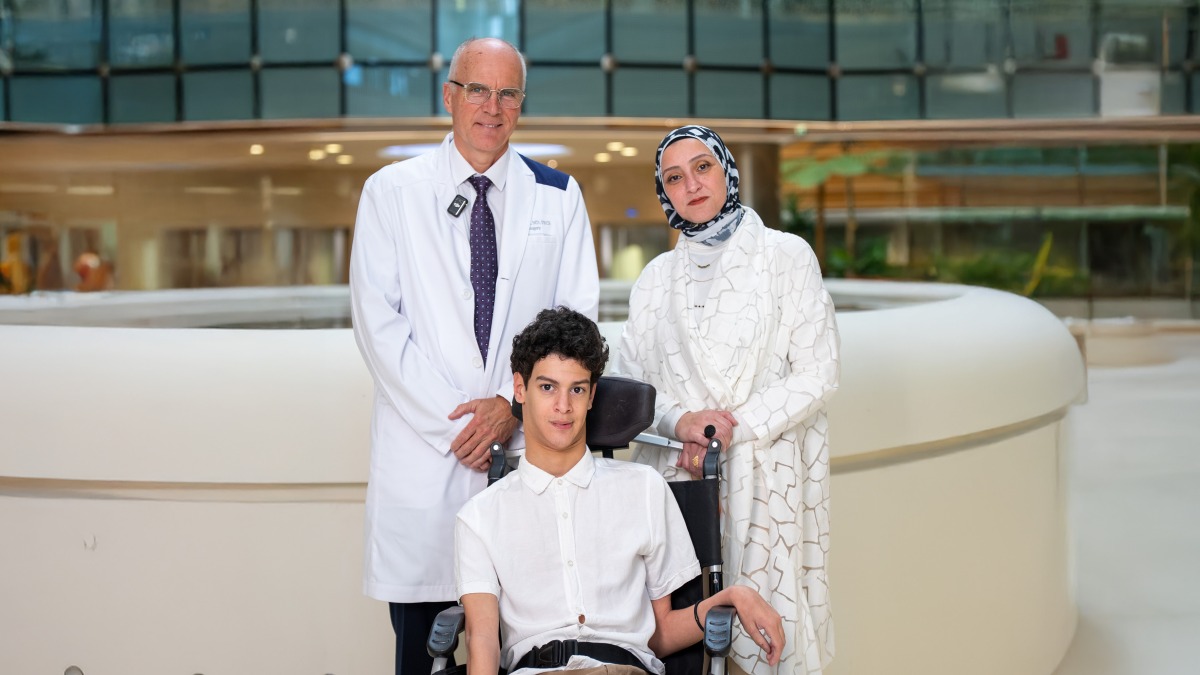 Dr. Ian Pople, Chief of Neurosurgery at Sidra Medicine with Adam and his mother.