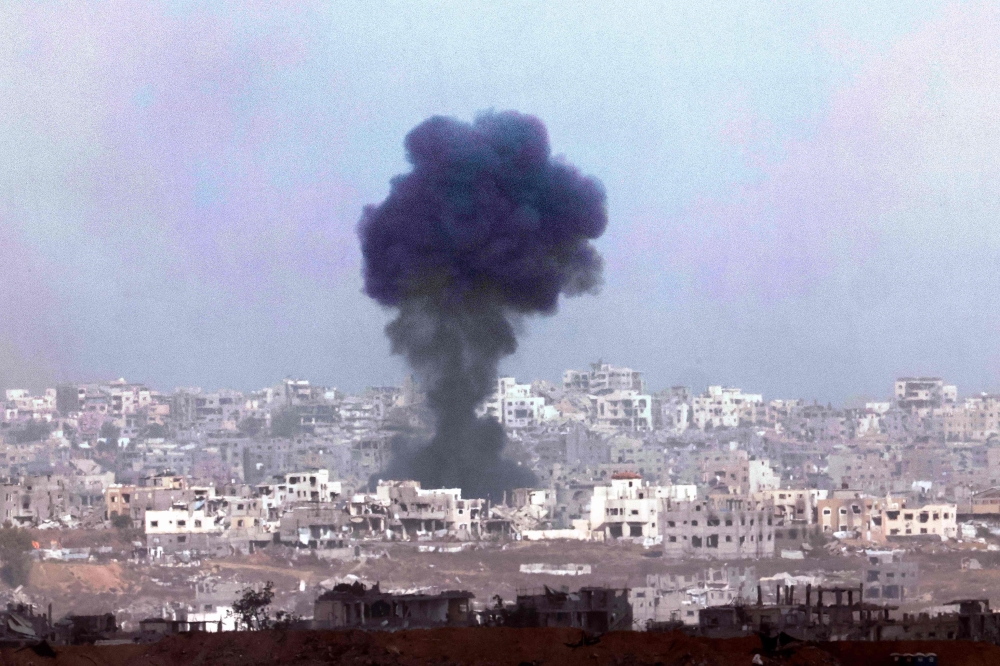 Smoke billowing above destroyed buildings during Israeli bombardment in the besieged Palestinian territory on May 27, 2025. (Photo by Jack Guez / AFP)