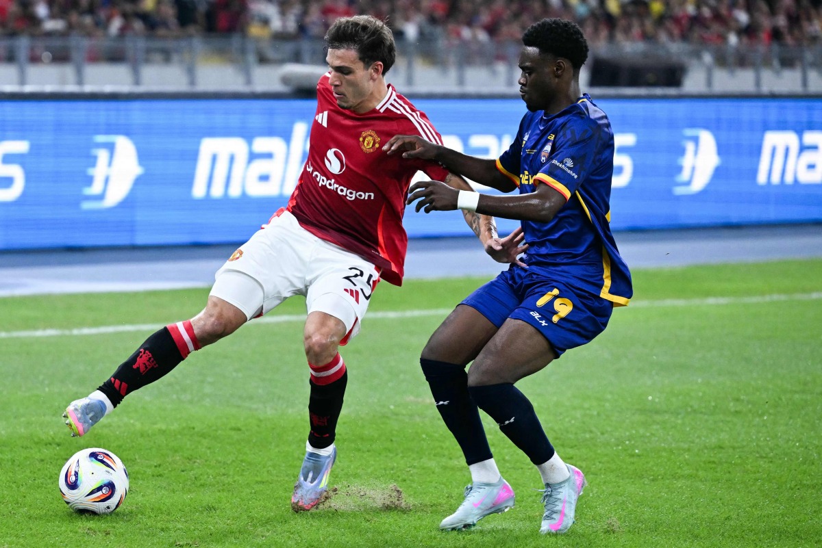 Manchester United's Manuel Ugarte (L) fights for the ball with Asean All-Stars Yaya Dukuly (R) the exhibition friendly football match between Manchester United and Asean All-Stars at the National Stadium Bukit Jalil in Kuala Lumpur on May 28, 2025. (Photo by Mohd RASFAN / AFP)