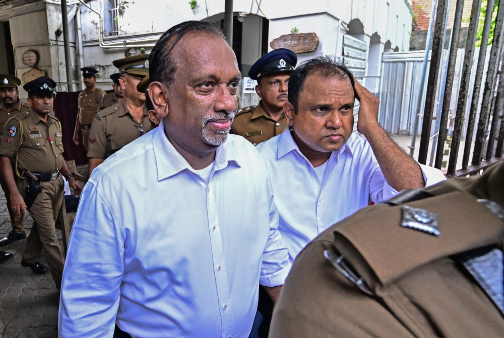 Sri Lanka's former sports minister Mahindananda Aluthgamage (left) and former trade minister Anil Fernando are escorted by police outside a court in Colombo on May 29, 2029 (Photo by Ishara S. Kodikara/ AFP)