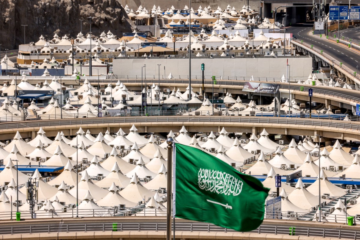 A Saudi flag flies as behind are pictured tents housing Muslim pilgrims in Mina near Islam's holy city of Mecca ahead of the annual Hajj pilgrimage on June 1, 2025. (Photo by Hazem Bader / AFP)
