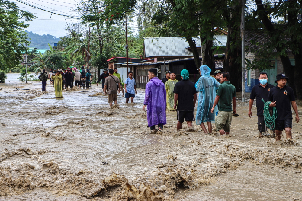 Residents wade through a flooded street following heavy rainfall in the Khurai Konsam Leikai village in Imphal East district of India's Manipur state on May 31, 2025. (Photo by AFP)