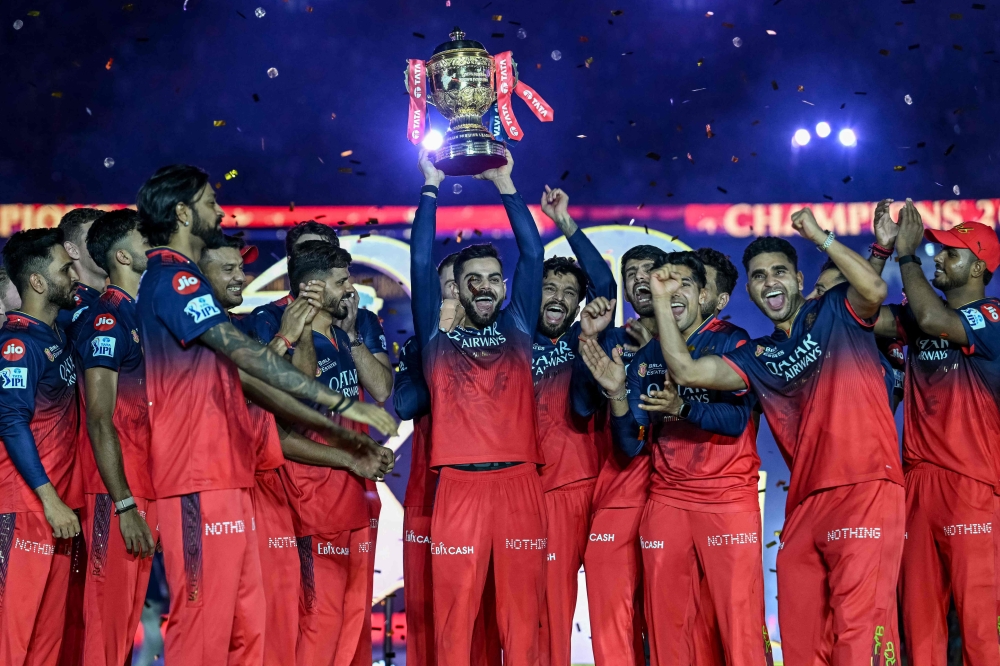 Royal Challengers Bengaluru's Virat Kohli, along with his teammates, celebrates with the trophy after winning the Indian Premier League (IPL) Twenty20 final cricket match against Punjab Kings at the Narendra Modi Stadium in Ahmedabad on June 4, 2025. (Photo by Arun Sankar / AFP)
