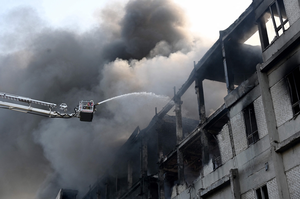 A firefighter extinguishes a fire at a civilian plant following Russian powerful attacks on the Ukrainian city of Kharkiv early on June 7, 2025. (Photo by Sergey Bobok / AFP)