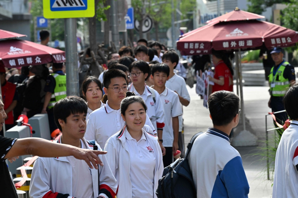 Students queue to enter a school during China's National College Entrance Examination (NCEE), known as “gaokao”, outside a high school in Beijing on June 7, 2025. (Photo by Adek Berry / AFP)