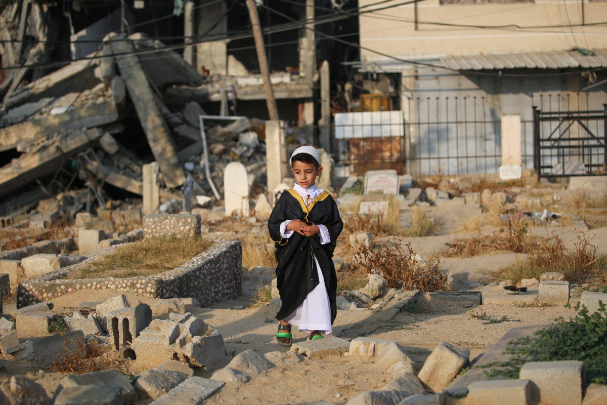 A Palestinian child visits the grave of a loved one on the first day of the Muslim Eid al-Adha festival in Nuseirat, in the central Gaza Strip, on June 6, 2025. (Photo by Eyad BABA / AFP)
