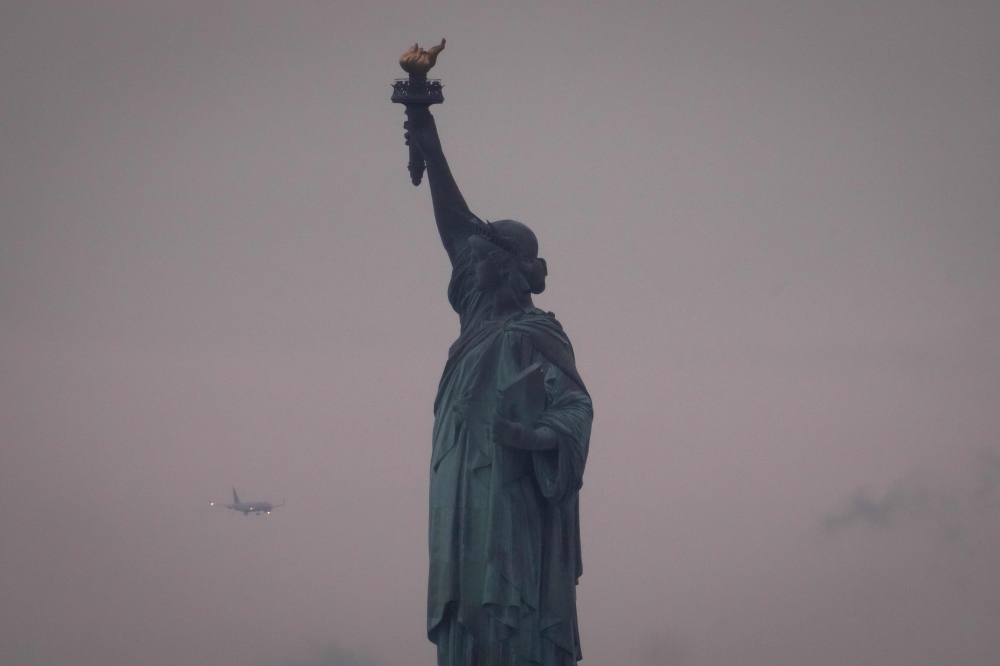 A plane prepares to land at Newark Liberty International Airport behind the Statue of Liberty on June 8, 2025 in New York City. Adam Gray/Getty Images/AFP 