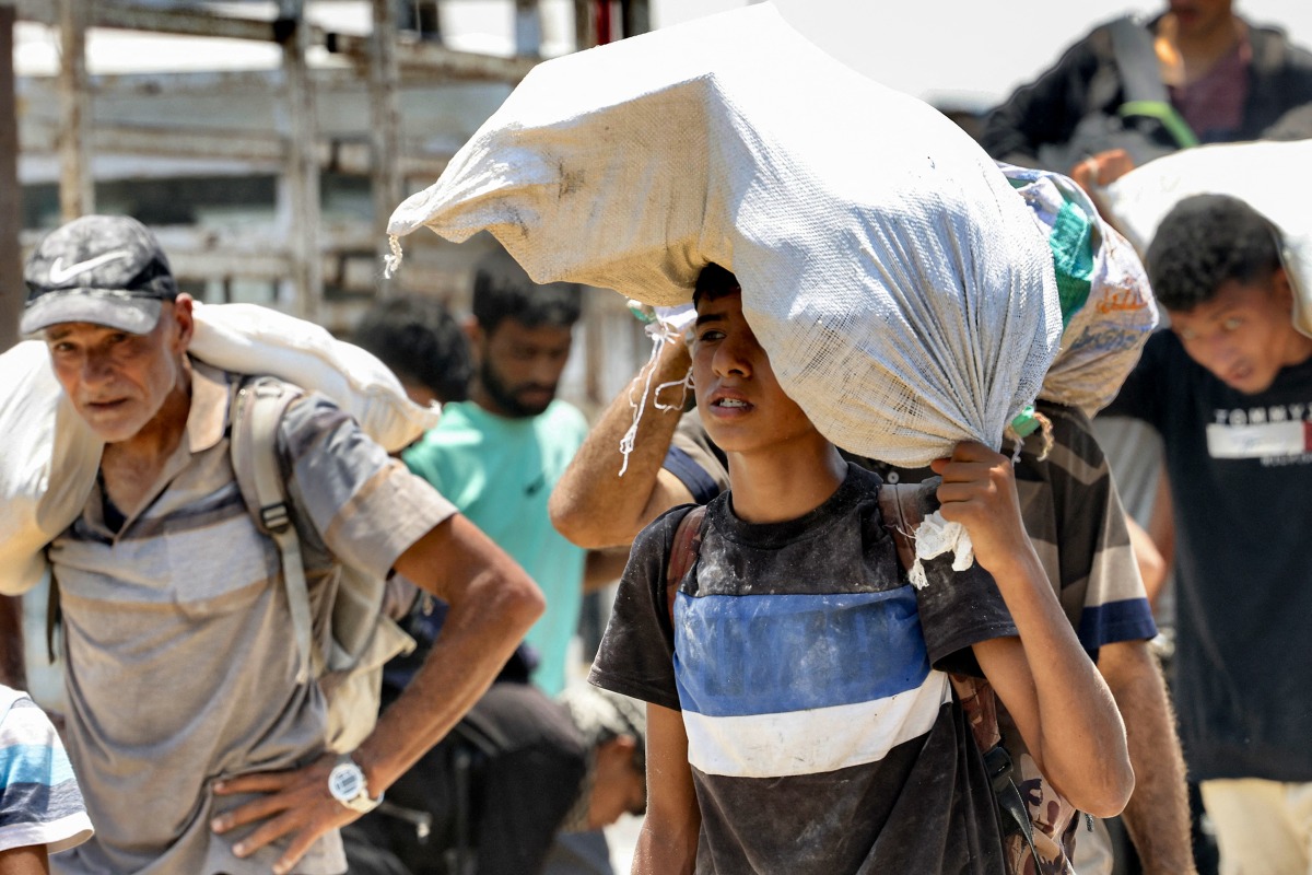 Photo used for representational purposes. Displaced Palestinians receive humanitarian aid packages from a US-backed foundation in Rafah in the southern Gaza Strip on June 10, 2025. Photo by AFP.
