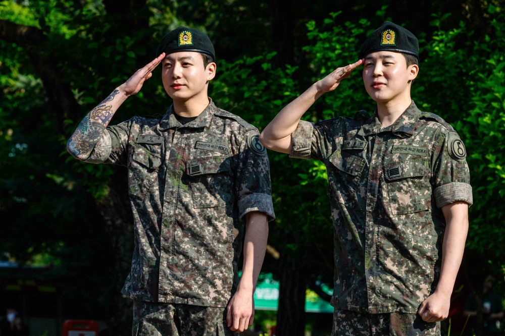 Jungkook (left) and Jimin of K-pop supergroup BTS salute at an outdoor sporting facility in Yeoncheon on June 11, 2025, shortly after their release from 18 months of South Korean military service. (Photo by Anthony Wallace / AFP)