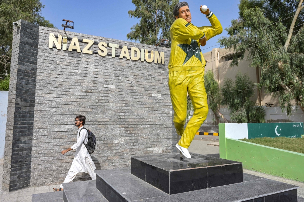 A commuter walks past the statue of Pakistan's former cricket player Wasim Akram outside the Niaz Stadium in Hyderabad on June 12, 2025. (Photo by Akram Shahid / AFP)