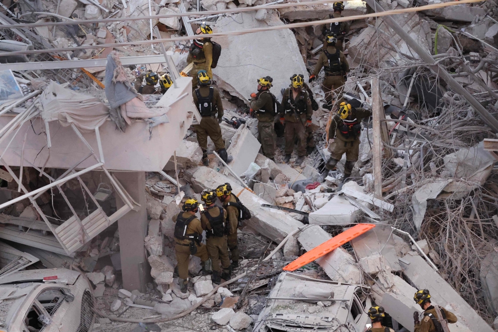 Responders work amid building rubble following a strike by an Iranian missile in the Israeli city of Bat Yam, early on June 15, 2025. (Photo by Jack Guez / AFP)