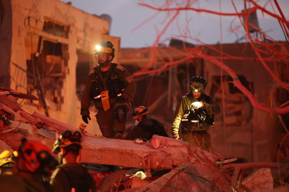 Responders search through building rubble following a strike by an Iranian missile in the Israeli city of Bat Yam, south of Tel Aviv, early on June 15, 2025. (Photo by Jack Guez / AFP)