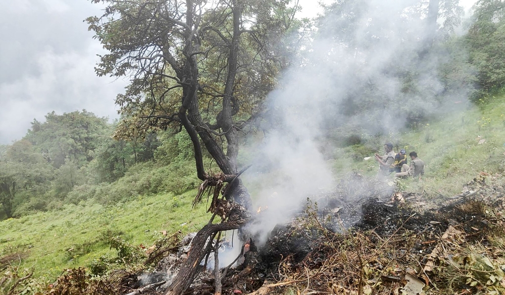 This handout photograph taken on June 15, 2025 and released by the State Disaster Response Force (SDRF) of India's Uttarakhand state shows smoke billowing from the site of a chopper crash near Gaurikund. (Photo by Uttarakhand's State Disaster Response Force (SDRF) / AFP) 
