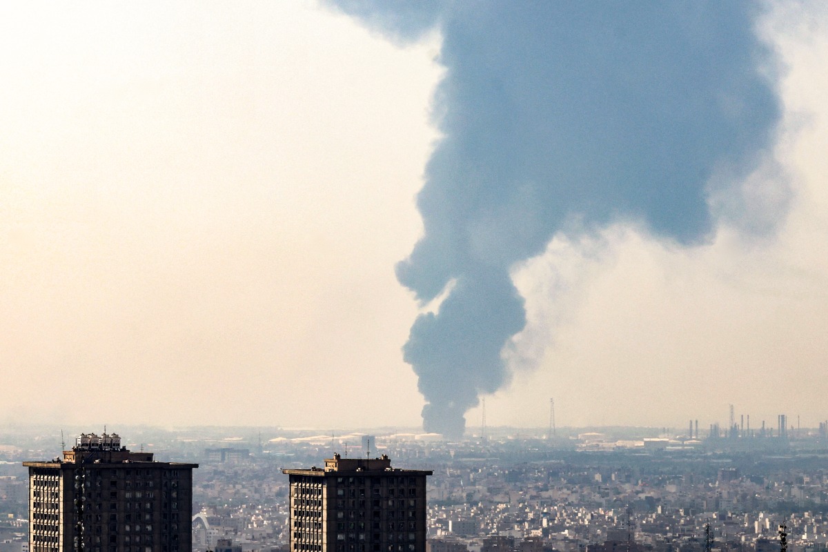 A plume of heavy smoke rises over an oil refinery in southern of Tehran, after it was hit in an overnight Israeli strike, on June 15, 2025. Photo by Atta KENARE / AFP.