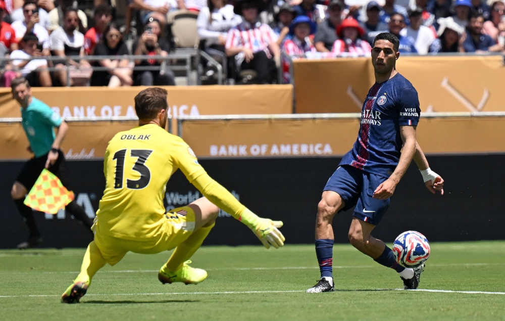 Paris Saint-Germain's Moroccan midfielder #02 Achraf Hakimi (R) passes the ball in front of Atletico Madrid's Slovenian goalkeeper #13 Jan Oblak during the Club World Cup 2025 on June 15, 2025. (Photo by Patrick T. Fallon / AFP)