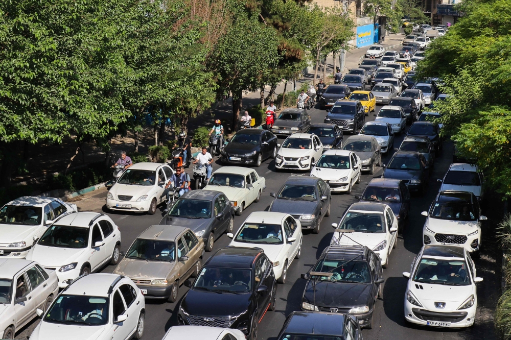 Vehicles await in traffic as people get out of Tehran through an artery in the city's west on June 15, 2025. (Photo by Atta Kenare / AFP)
 
