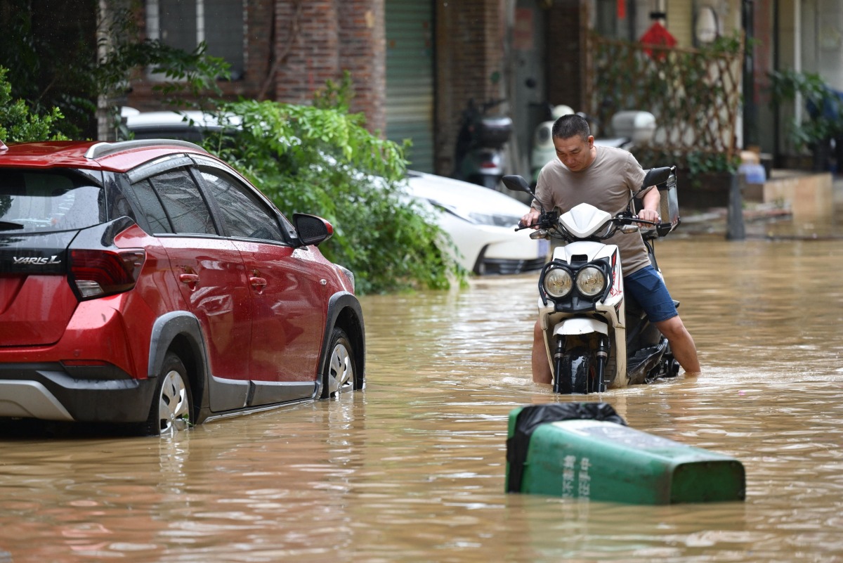 A man rides through a flooded street in Zhongshan, in China's southern Guangdong province on June 17, 2025. (Photo by AFP) 