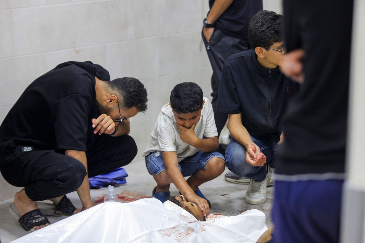 People mourn over the body of a loved one at the morgue of Al-Awda hospital, in Nuseirat camp in central Gaza on June 20, 2025, after several Palestinians were killed as they reportedly headed to a food distribution centre in the war-stricken Gaza Strip. Photo by AFP