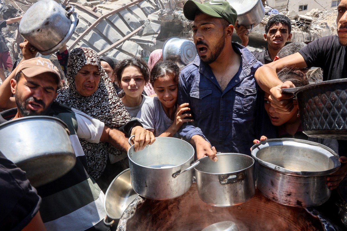 Palestinians try to get food at a charity kitchen providing hot meals in Rimal neighbourhood in Gaza City on June 18, 2025. Photo by Omar AL-QATTAA / AFP
