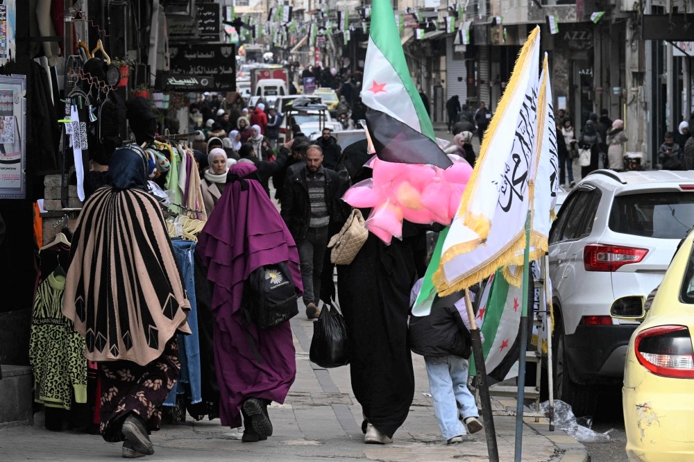 File: People walk past shops in Homs on February 10, 2025. (Photo by Louai Beshara / AFP)

