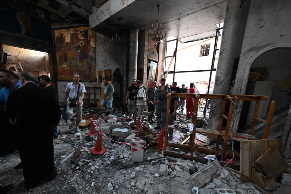 People and rescuers inspect the damage at the site of a reported suicide attack at the Saint Elias church in Damascus' Dwelaa area on June 22, 2025. (Photo by Louai Beshara / AFP)